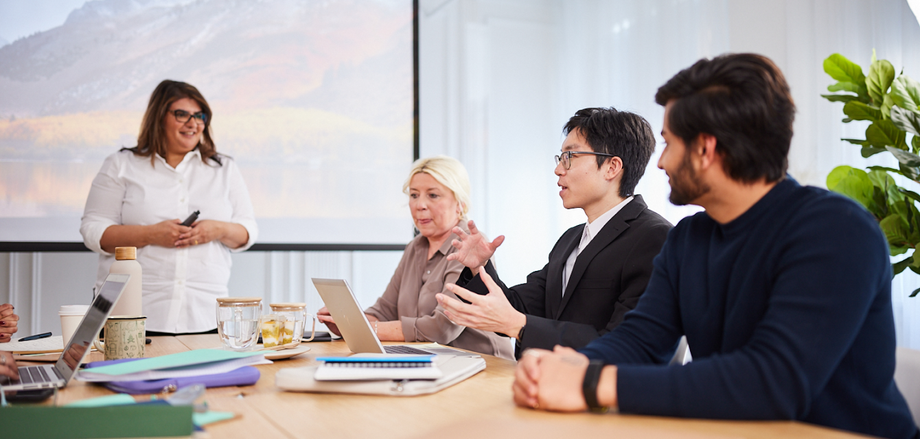 A group of people sitting around a boardroom table talking